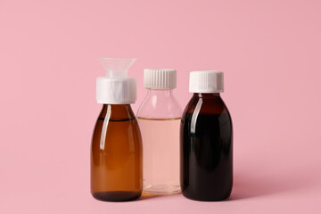 Bottles of cough syrup on pink background