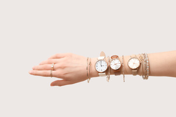 Female hand with golden wristwatches and bracelets on white background