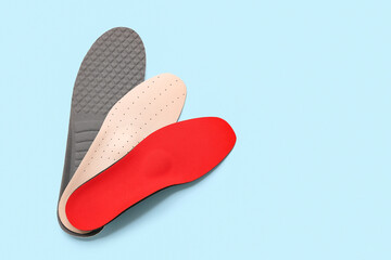 Different orthopedic insoles on light blue background with space for text