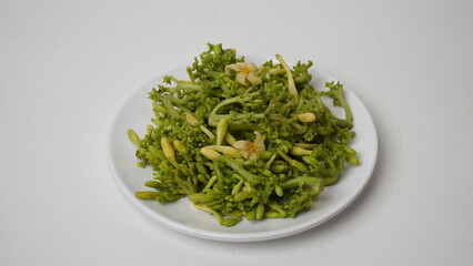A collection of raw papaya flowers placed on a white plate with a white base and background (isolated white).