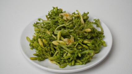 A collection of raw papaya flowers placed on a white plate with a white base and background (isolated white).