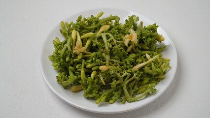A collection of raw papaya flowers placed on a white plate with a white base and background (isolated white).