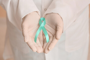 Mature female doctor with teal ribbon, closeup. Cervical Health Awareness Month