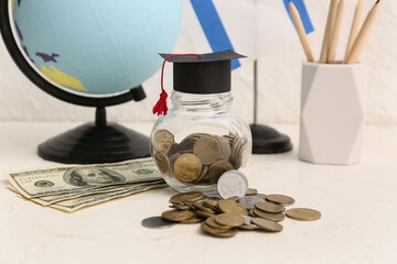 Jar of money and globe on white table, closeup. Student loan concept