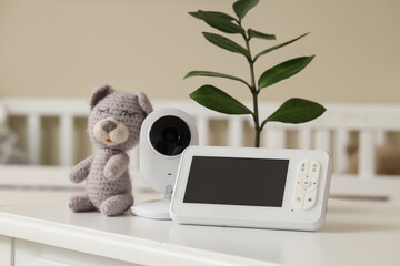 Baby monitor with toy and plant on table in children's bedroom, closeup