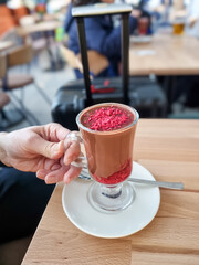 Unrecognisable person enjoying a beautiful cup of hot chocolate with raspberry on top and in the drink