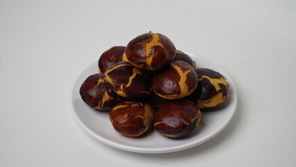 A collection of raw jengkol placed on a white plate with a white base and background (isolated white).