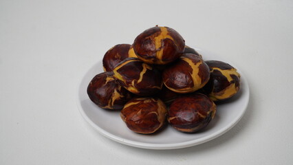 A collection of raw jengkol placed on a white plate with a white base and background (isolated white).