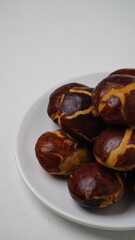 A collection of raw jengkol placed on a white plate with a white base and background (isolated white).