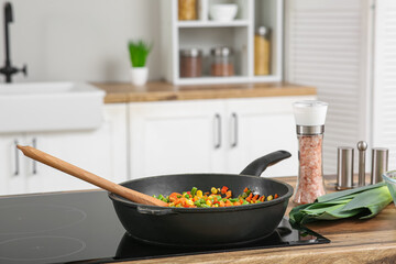 Frying pan with roasted vegetables on stove in kitchen