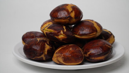 A collection of raw jengkol placed on a white plate with a white base and background (isolated white).