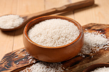 Bowl with raw rice on wooden background