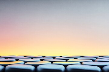 Obraz premium Smooth dark stones gently curve upward against a softly glowing pastel backdrop. AI Generated