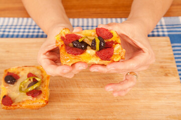 Caucasian white person holding pizza pieces on bamboo cutting board on blue napkin