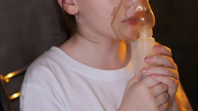 Little girl wearing a breathing medical mask. The girl does inhalation. Treatment of respiratory diseases. Little girl wearing a breathing medical mask. 
