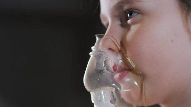 Little girl wearing a breathing medical mask. The girl does inhalation. Treatment of respiratory diseases. Little girl wearing a breathing medical mask. 