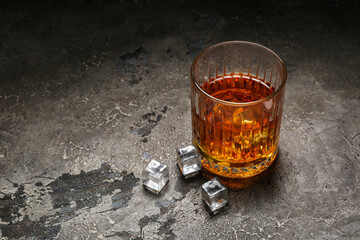 Glass of cold rum on grey grunge background