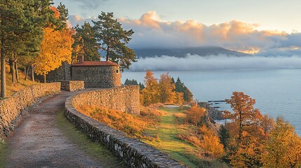 Obraz premium Autumnal coastal path with stone structure and lake view at sunrise.