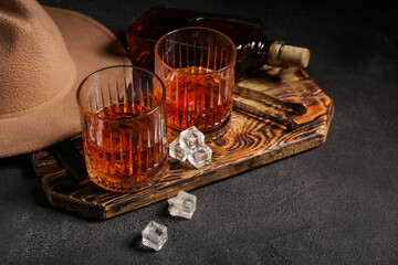 Composition with glasses of cold rum, hat and ice tongs on black grunge background