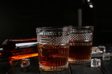Glasses of cold rum on black wooden table, closeup