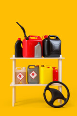 Shelf unit with canisters and car steering wheel on yellow background