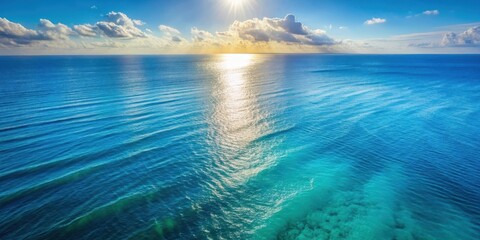 Fototapeta premium Aerial view of a serene blue ocean surface with gentle waves and sunlight on the water , aerial photography, natural beauty
