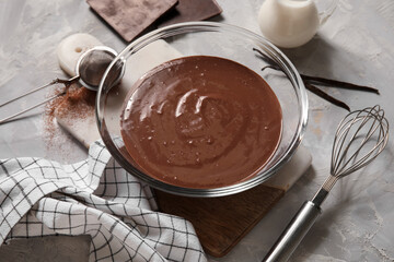 Bowl with tasty melted chocolate on grey background. Closeup