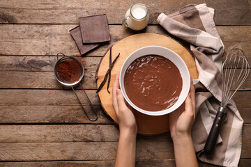 Female hands cooking tasty hot chocolate on wooden table. Top view