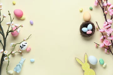  Frame made of Easter eggs, decor and blooming tree branches on beige background © Pixel-Shot