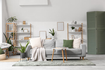 Obraz premium Interior of light living room with sofa, shelf units and green plants