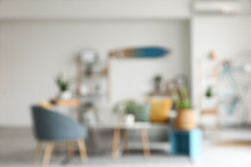 Blurred view of living room with sofa, shelf units and green plants
