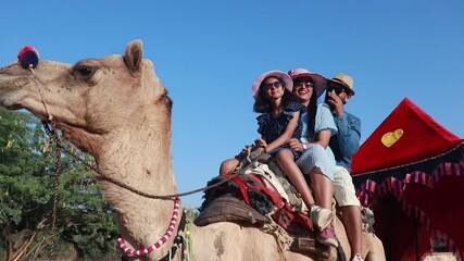 Young indian tourist family enjoying camel ride together having fun. People of india enjoy Rajasthan Safari Vacation and holidays.
