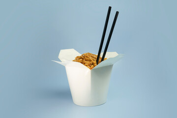 Wok noodles Udon and rice with seafood and chicken in a box on black background. With chopsticks and sauce. Asian food to go