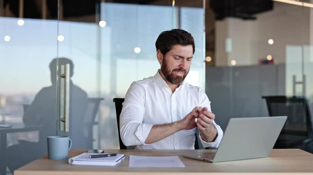 Stressed businessman has skin irritation. He sits at workplace desk and scratches neck, feeling strong itch and discomfort.