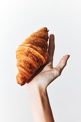 Person holding a croissant on a white background