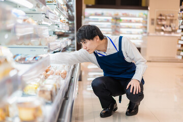 食品スーパーで品出しをする若いスタッフ