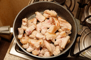 A pan of pork is cooking on a stove