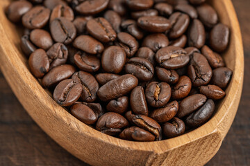 Close-up of roasted coffee beans in a wooden bowl. Rich aroma and texture of freshly roasted coffee.