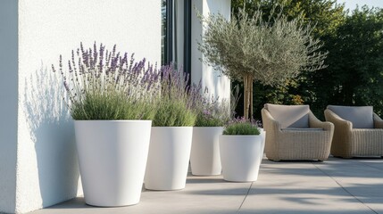 Three modern white plant pots on the terrace, next to them is an outdoor floor lamp, and in one of these flowerpots, there is lavender and other plants