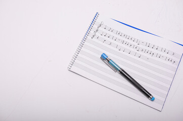 Composer writing music notes with pen on notebook on white table
