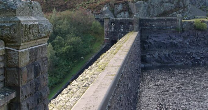 wide shot looking across the upstream slope face of the Caban Coch Dam when partially drained