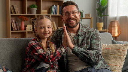 Joyful Caucasian dad male giving high five girl schoolgirl success gesture at home little child...