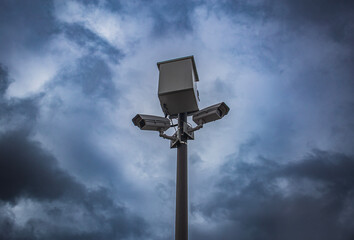 surveillance camera fining people and keeping control, against the background of severe thunderclouds with a thunderstorm. the problem of freedom and personal life in the 21st century
