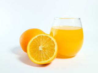 Fresh orange juice in a glass with whole and sliced oranges isolated on a white background