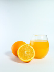Fresh orange juice in a glass with whole and sliced oranges isolated on a white background