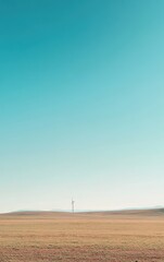 Obraz premium A wind turbine standing tall in an open field against a vibrant blue sky, symbolizing renewable energy and sustainability.