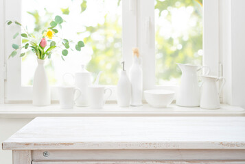 Bleached wooden table top on bright white kitchen window sill interior background with kitchenware
