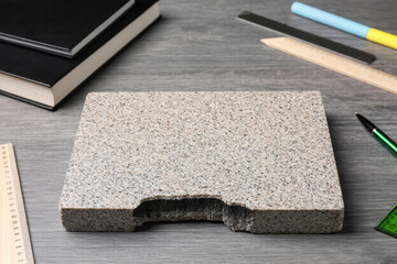A granite stone lies on the student's desk, next to books, a pen, a calculator, a protractor, the concept of gnawing the granite of science