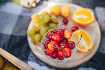 Bowl with juicy cherries on background of other fruits, top view