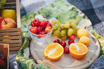 Colorful set of summer fruits and berries on a picnic: ripe cherries, oranges, grapes and plums